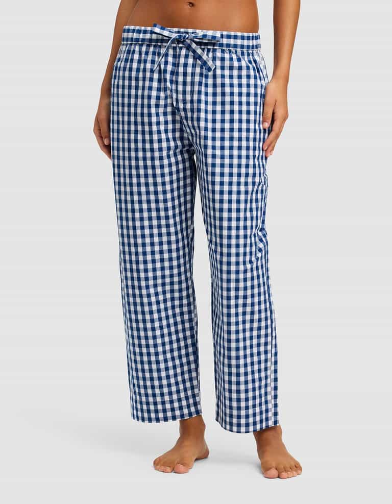 A woman wears Cozy Earth’s Women’s Sutton Cropped Pajama Pant, featuring a blue and white checkered pattern and drawstring waist, standing barefoot against a plain white background. |Color:Pacific Gingham