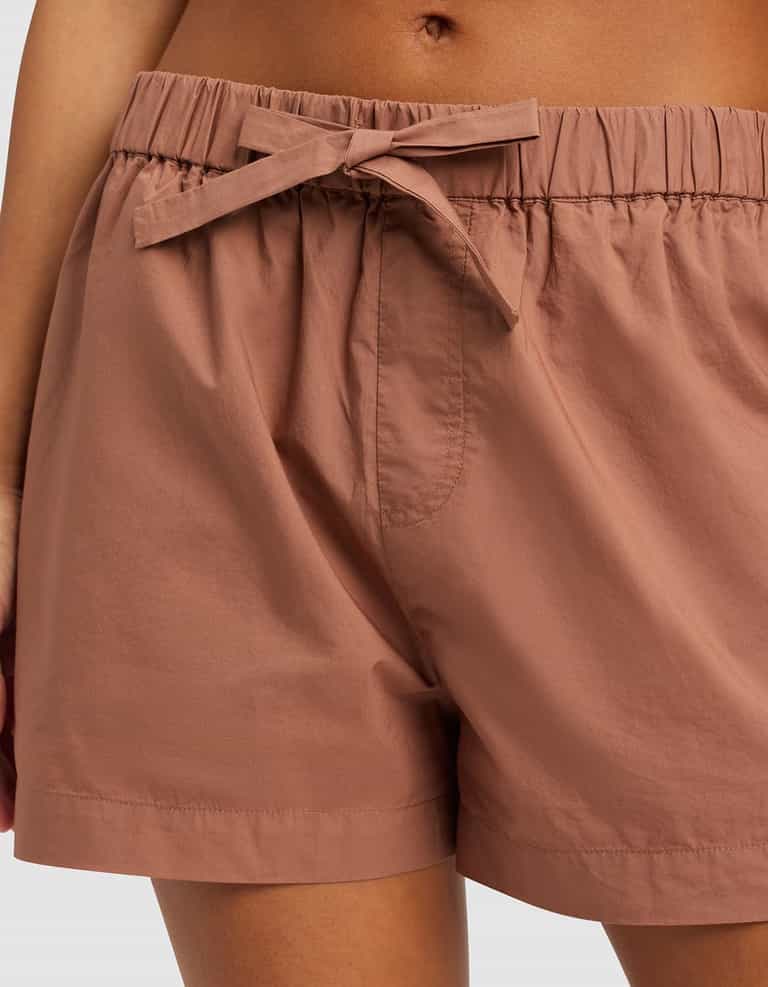 Close-up of a person wearing Cozy Earth’s Women's Sutton Pajama Short—high-waisted, light brown, with an elastic waistband, fabric tie front, relaxed fit, and lightweight material.|Color:Saddle