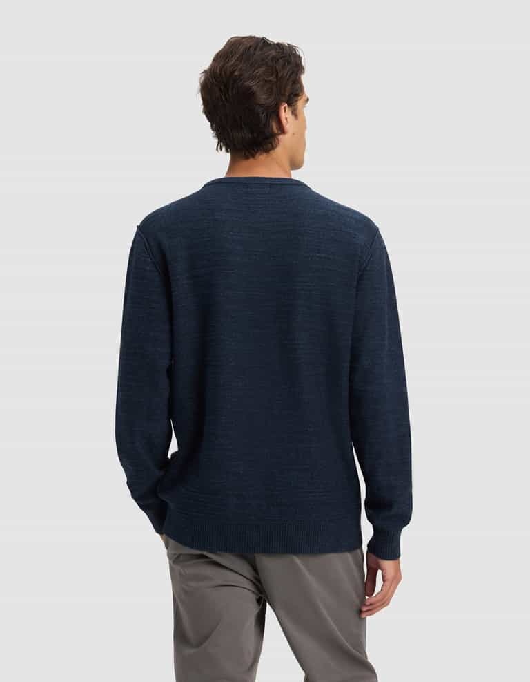 A man stands facing away from the camera, wearing Cozy Earth's Men's Tate Crewneck in dark blue and gray pants against a plain light gray background.|Color:Eclipse