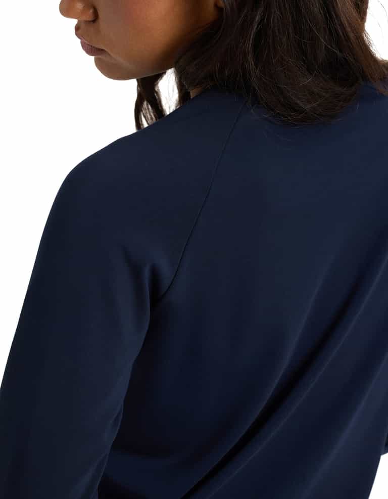 A woman wears the Cozy Earth Women's Brushed Bamboo Pullover Crew, a long-sleeve dark blue top, shown from the side and back with her face partially visible.|Color:Navy