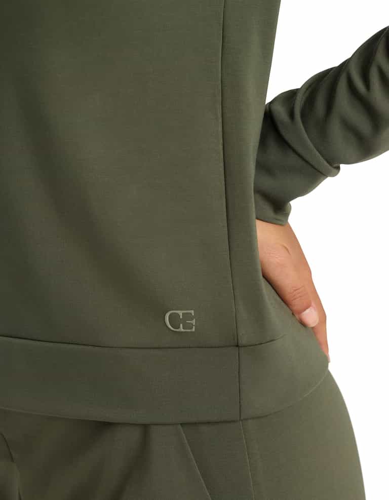 Close-up of a person in the Cozy Earth Women's Brushed Bamboo Pullover Crew in olive green, hand on hip. A small "CE" logo appears near the hem of the top against a white background.|Color:Olive