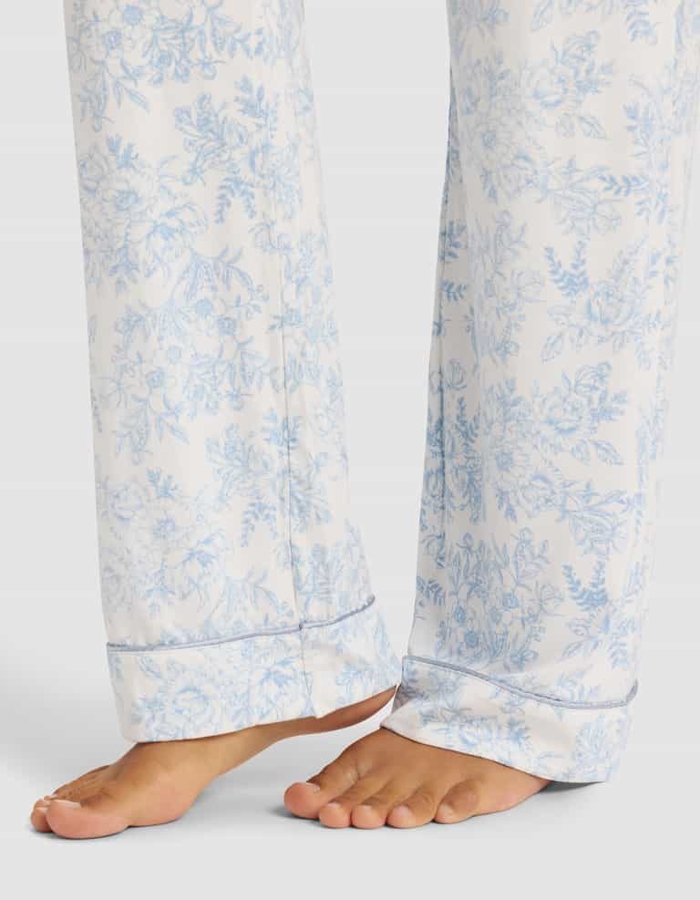 A close-up of a person’s bare feet wearing Cozy Earth Women's Bamboo Stretch-Knit Pajama Pant, featuring a light blue floral pattern, standing on a plain surface.|Color:Sky Toile