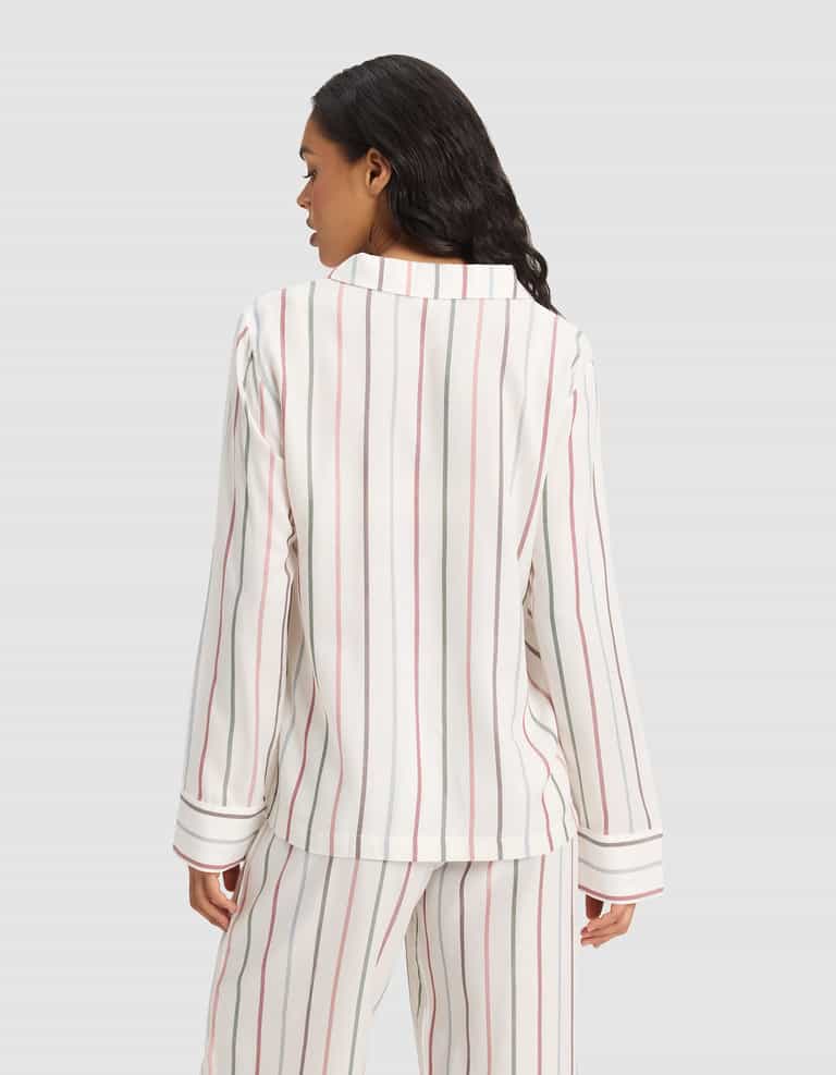A woman with long dark hair faces away, modeling Cozy Earth's Women's Soft Woven Long Sleeve Pajama Top in a white fabric with vertical red, black, and beige stripes. The background is plain light gray. |Color:Cottage Stripe