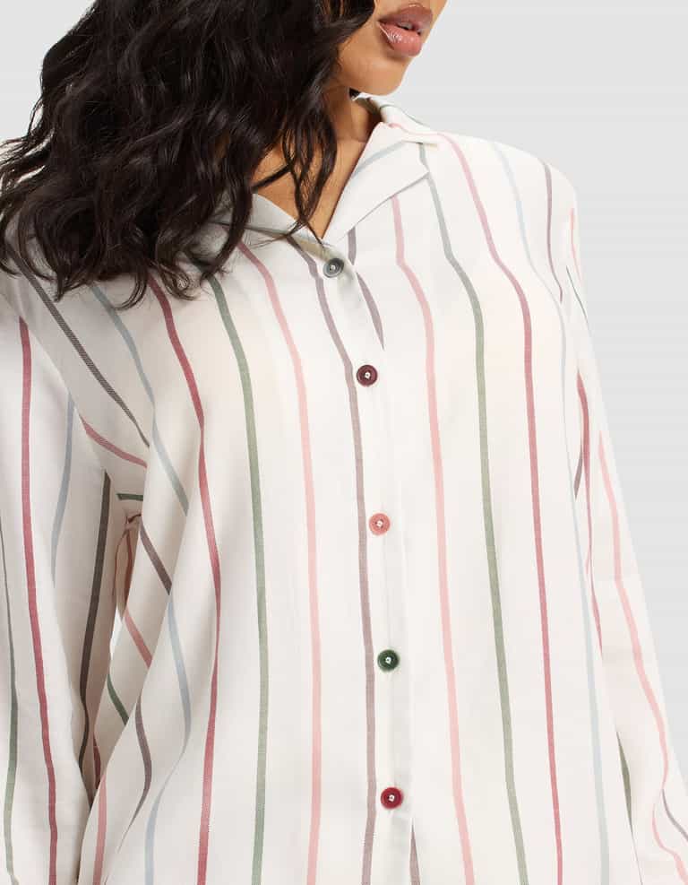 A woman models the Cozy Earth Women's Soft Woven Long Sleeve Pajama Top, featuring vertical pastel pink, green, and gray stripes with multicolored buttons. Her wavy dark hair partially covers her face.|Color:Cottage Stripe