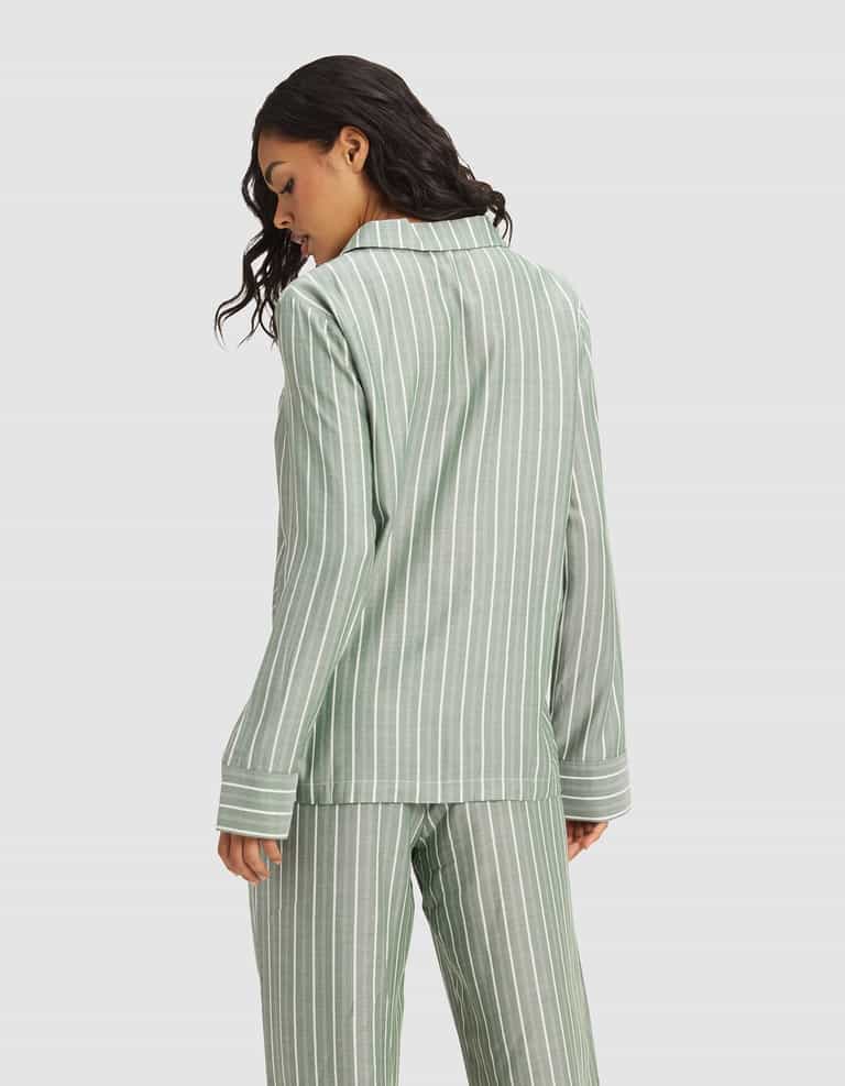 A woman with wavy dark hair models the Cozy Earth Women's Soft Woven Long Sleeve Pajama Top in sage green with white stripes, shown from the back against a plain light gray background.|Color:Striped Jasper