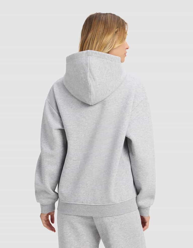 A woman with shoulder-length blonde hair is seen from behind wearing the Cozy Earth Women's Cityscape 2.0 Hoodie in light gray, with matching sweatpants, against a plain white background.|Color:Heather Grey