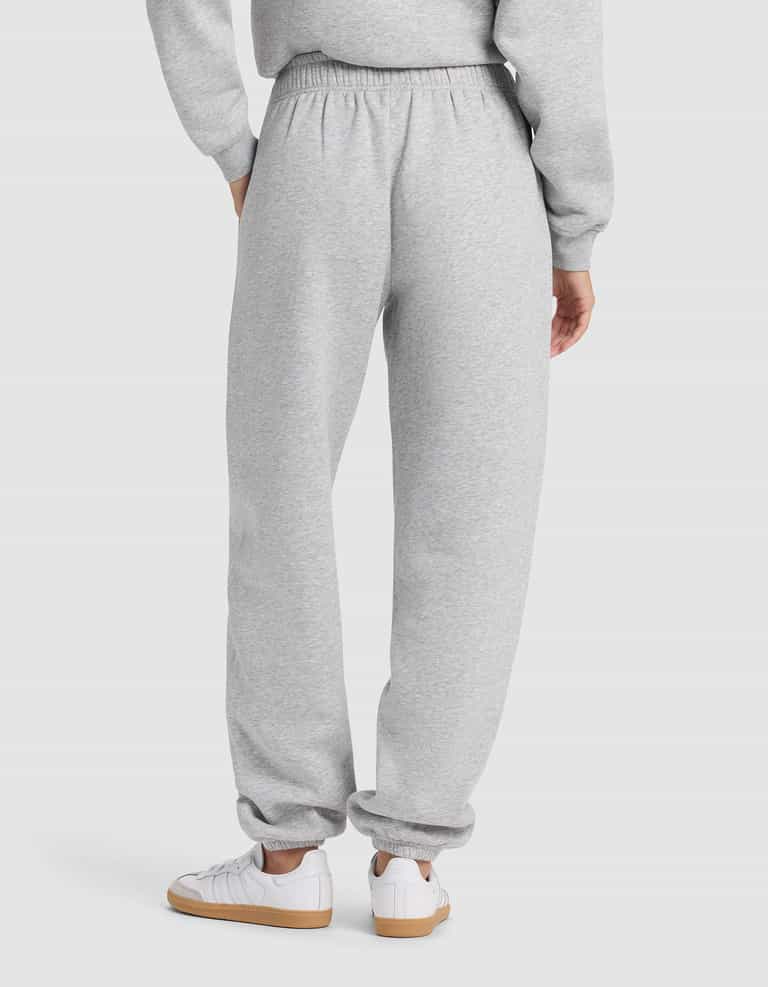 A person is shown from the back wearing Cozy Earth's Women's Cityscape 2.0 Sweatpant in light gray with a matching sweatshirt and white sneakers with tan soles, against a plain, light-colored background.|Color:Heather Grey