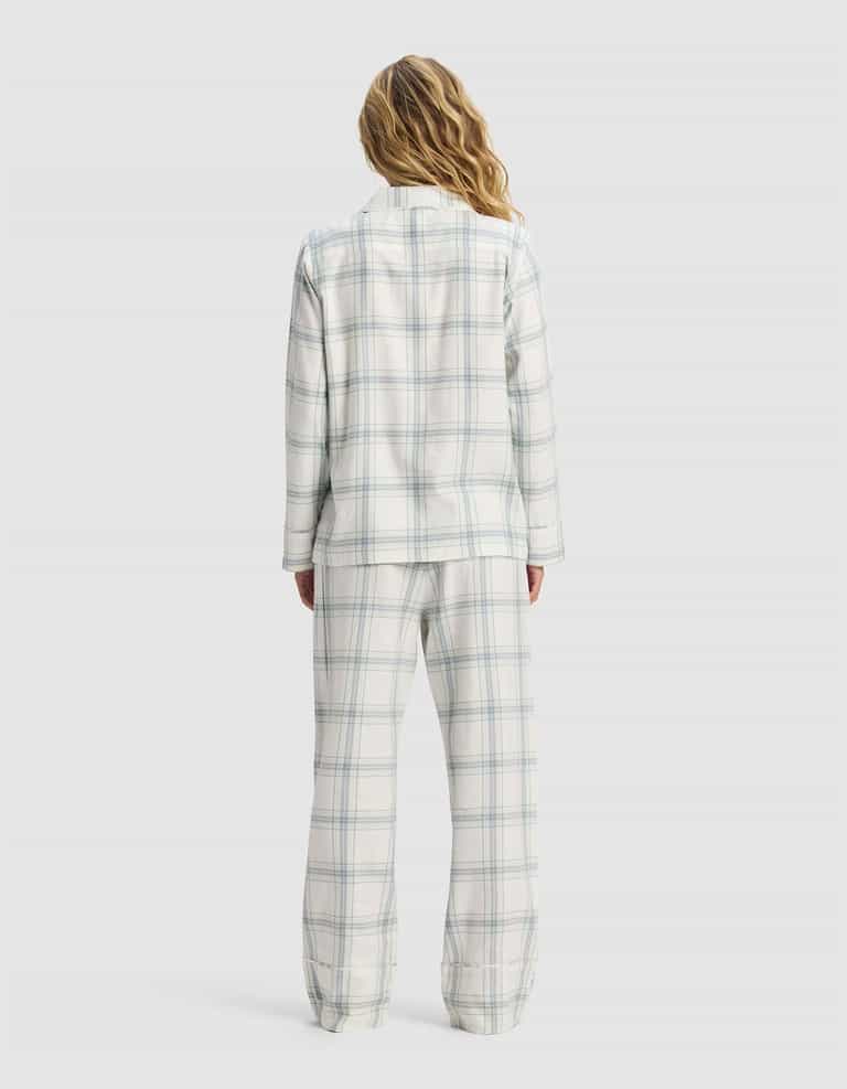 A woman with long, wavy hair stands with her back to the camera, wearing the Cozy Earth Women's Farmhouse Long Sleeve Pajama Set in white and light blue plaid against a plain light background.|Color:Wintergreen Plaid