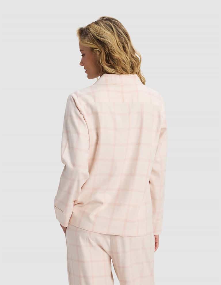 A woman with wavy blonde hair is seen from the back, wearing the Cozy Earth Women's Farmhouse Long Sleeve Pajama Top in pale pink plaid, paired with matching pants, against a plain light gray background.|Color:Quartz Plaid
