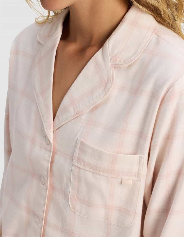 A close-up of a person wearing the Cozy Earth Women's Farmhouse Long Sleeve Pajama Top in pink and white plaid, featuring a chest pocket and buttons, with the upper torso and part of the face visible.|Color:Quartz Plaid