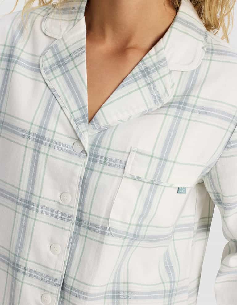 A person is wearing the Cozy Earth Women's Farmhouse Long Sleeve Pajama Top—a white top with light blue and green plaid, buttons, collar, and chest pocket. Only the upper body and part of the face are visible.|Color:Wintergreen Plaid