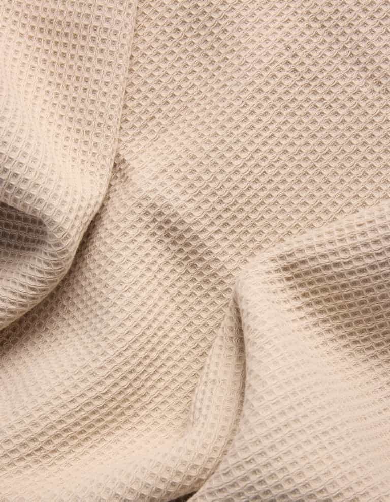 The Cozy Earth Waffle Bath Towel Set features beige waffle-textured fabric with a grid-like pattern, shown draped in soft folds. |Color:Birch