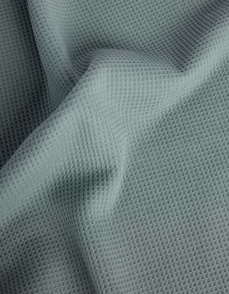 The Cozy Earth Waffle Bath Towel Set features light gray, waffle-textured fabric with a soft, grid-like pattern and gentle folds across the surface. |Color:Brook