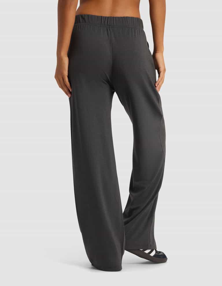 A woman is shown from the back wearing Cozy Earth's Women's Brushed Bamboo Wide Leg Pull-On Pant in dark gray with black sandals, posed against a plain white background.|Color:Charcoal