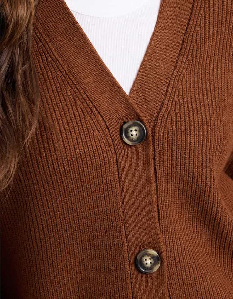 Close-up of a person wearing Cozy Earth's Oversized Classic Cardigan in ribbed brown with two dark buttons over a white top. Part of long brown hair is visible on the left side.|Color:Spice