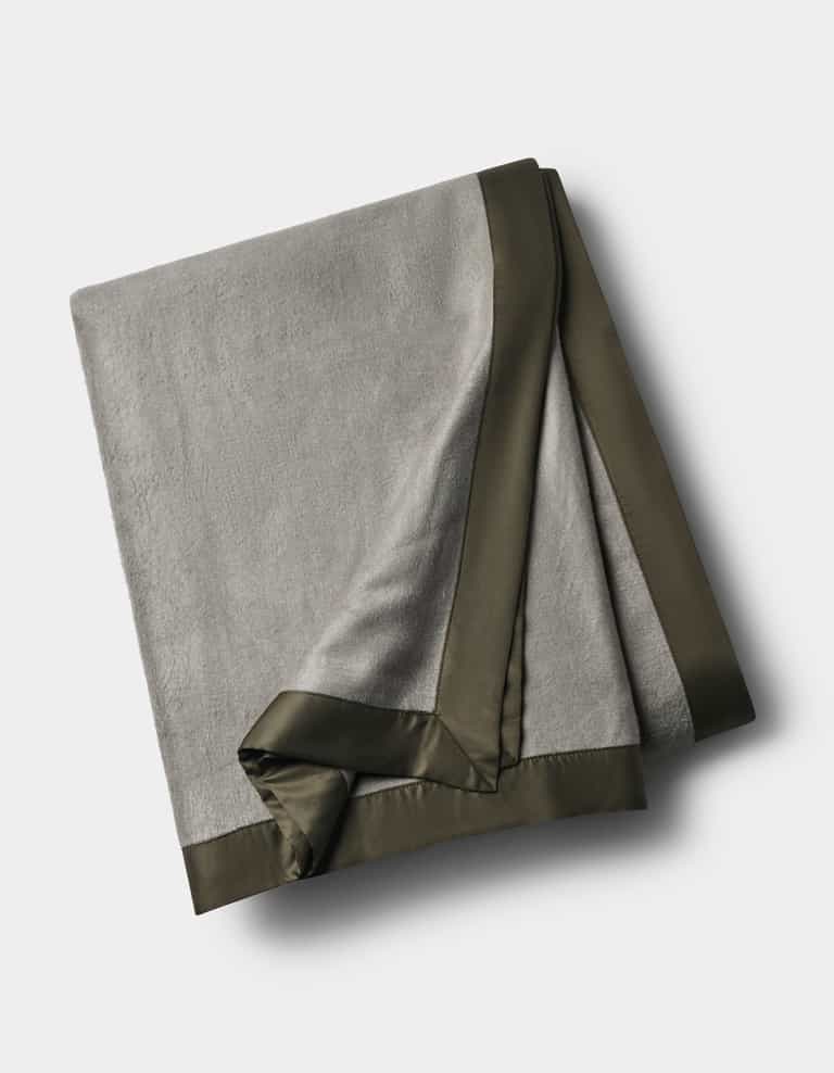 The Cozy Earth Bamboo Blanket, in light gray with a dark satin border, is neatly folded and displayed on a white background.|Color:Sage/Olive