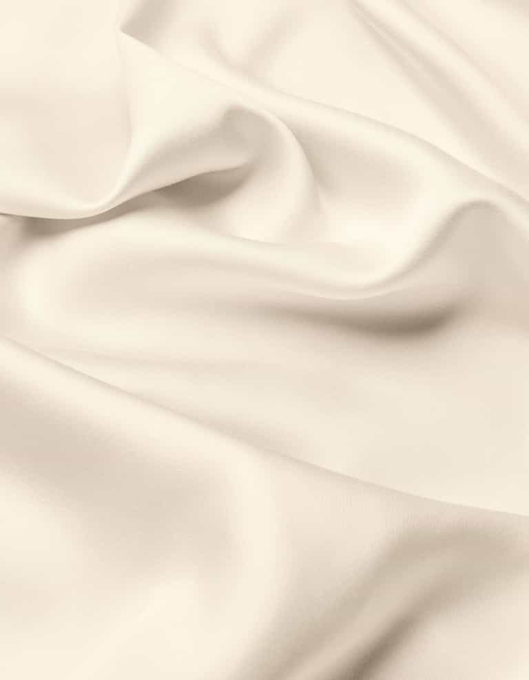 A close-up of the Cozy Earth Bamboo Flat Sheet highlights its smooth, cream-colored fabric with soft folds and gentle shadows, offering a sense of texture and elegance.|Color:Creme