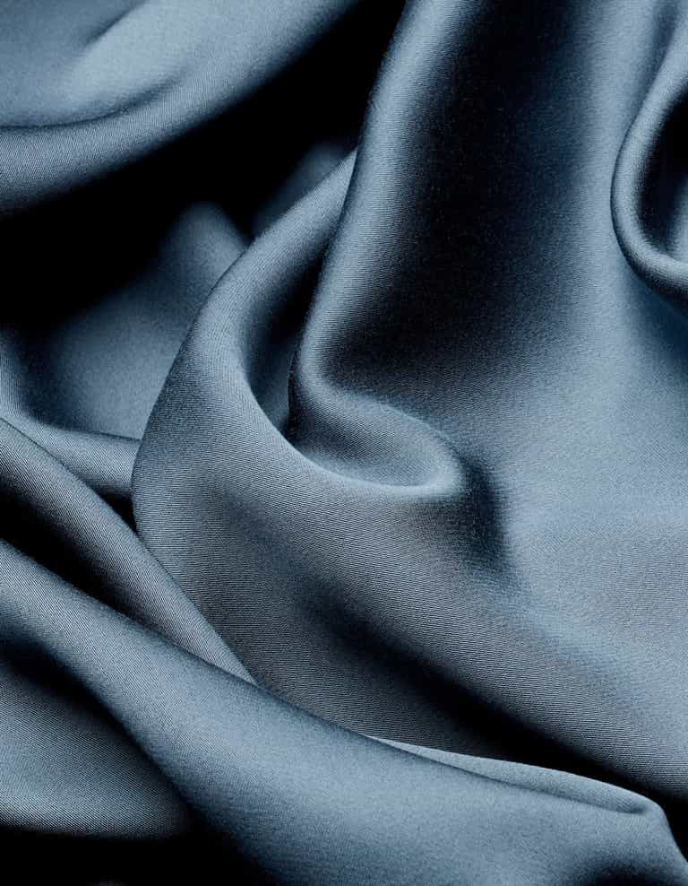 Close-up of the Cozy Earth Bamboo Flat Sheet in dark blue, featuring smooth, shiny fabric with soft folds and creases for a luxurious, elegant texture.|Color:Pacific Blue