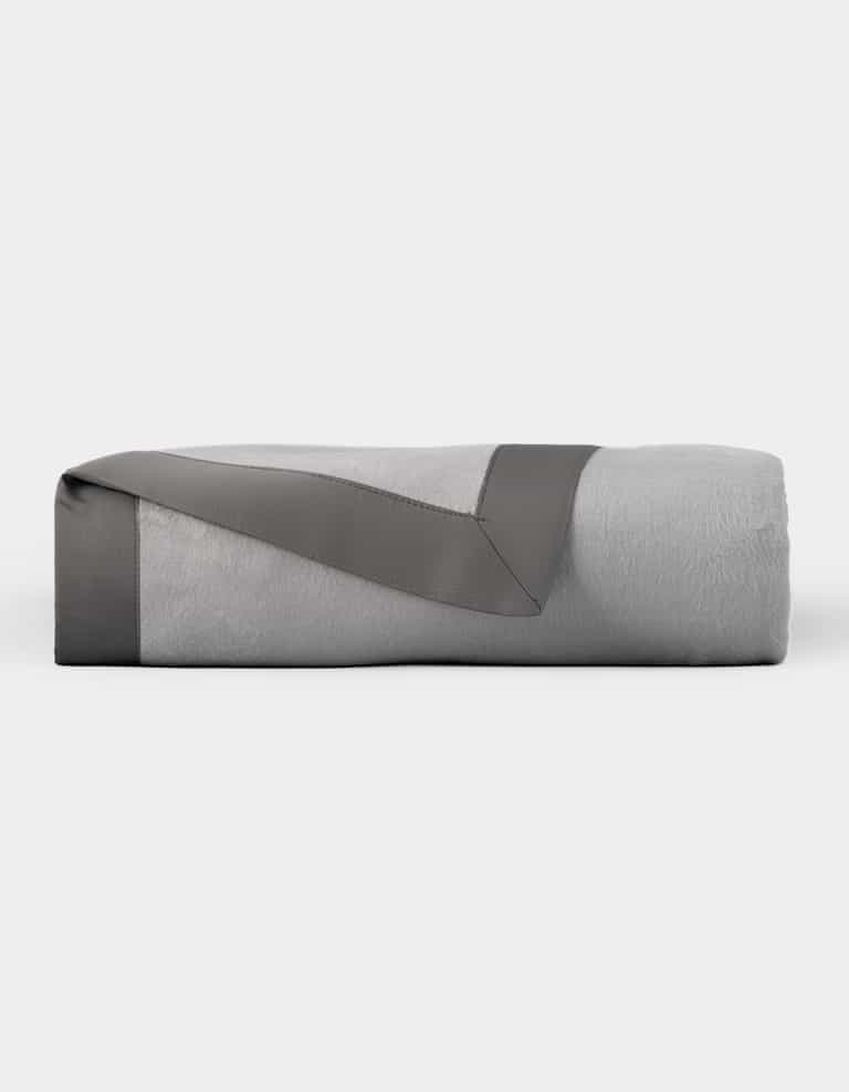 The Cozy Earth Bamboo Blanket is neatly folded, featuring a light gray color with a dark gray satin trim, and displayed on a plain white background. |Color:Dove Grey/Charcoal