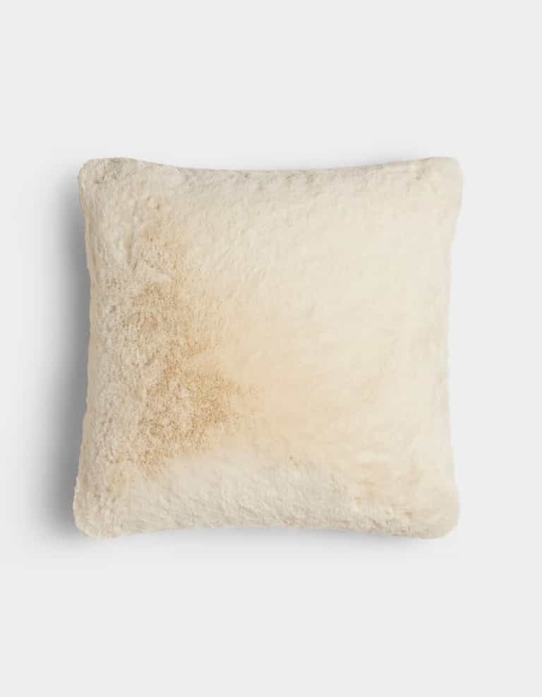 The Cuddle Pillow by Cozy Earth is a square, cream-colored, fluffy pillow featuring a light tan stain on the left side, shown against a plain white background.|Color:Creme