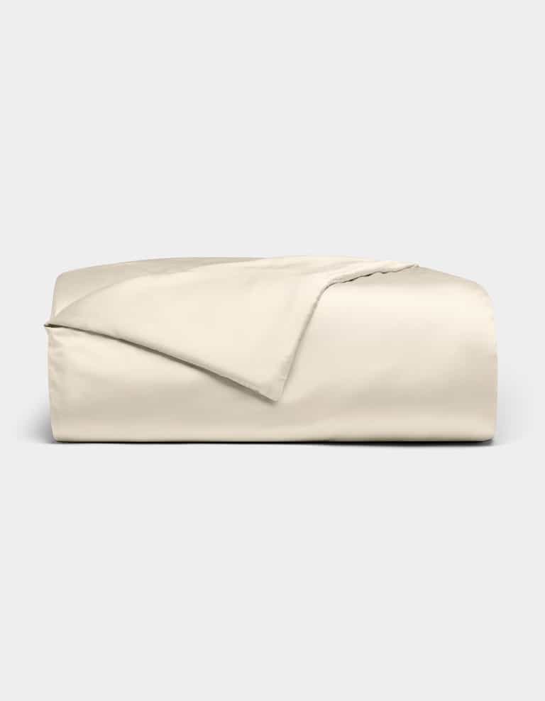 The Cozy Earth Bamboo Duvet Cover is shown neatly folded in light beige, with one corner turned back, set against a plain light gray background.|Color:Creme
