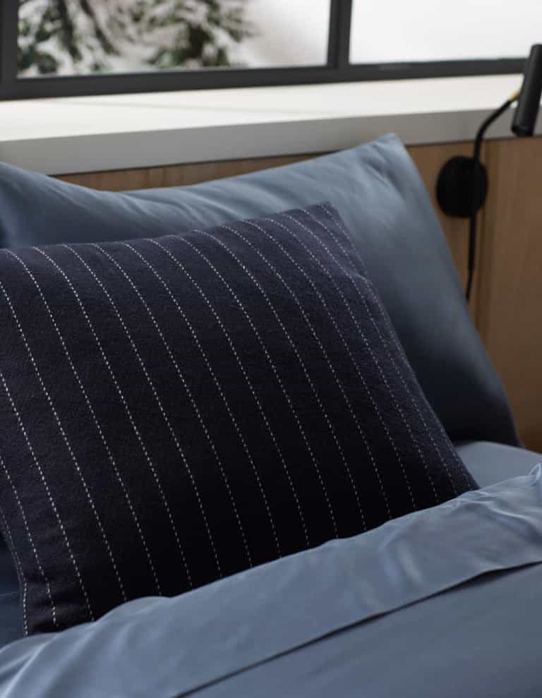 Blue bedding with a Cozy Earth Florence pillow on a bed in a bedroom setting. |Color:Navy