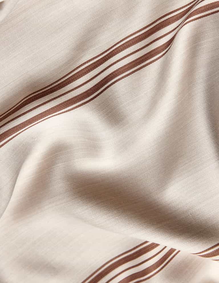 A close-up of Cozy Earth's Bamboo Sheet Set in beige, featuring brown parallel stripes, gentle folds, and a smooth, slightly shiny finish.|Color:Baja Stripe in Maple
