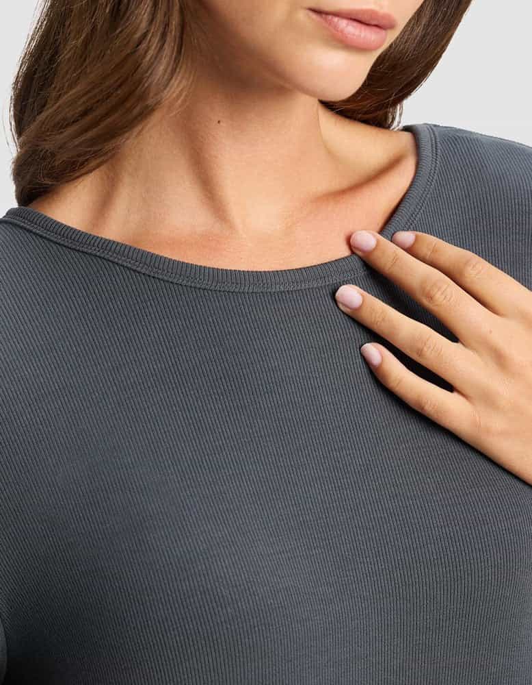 A woman in the Cozy Earth Women’s Bamboo Rib-Knit Boyfriend Sleep Dress in dark gray gently rests her manicured hand on her chest, with only her mouth, neck, and upper torso visible.|Color:Graphite